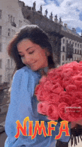 a woman is holding a bouquet of pink roses in front of a building .