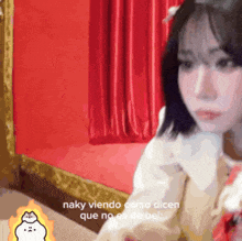 a woman is sitting in front of a red curtain with the words " naky viendo como dicen que no es de bel " below her