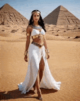 a woman in a white dress is standing in front of two pyramids