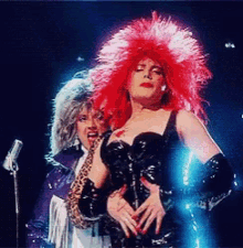 a woman in a red wig is standing next to another woman in a leopard print jacket