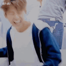 a person wearing a blue jacket and a white shirt is smiling and looking at the camera .