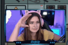 a woman wearing a cat ear headset is sitting in front of a computer monitor .