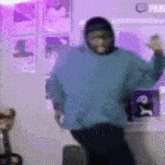 a person wearing a blue sweater and a mask is dancing in a room with purple lights .