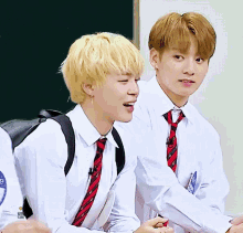 two boys wearing white shirts and red ties are smiling