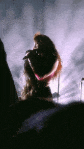 a woman with red hair is singing into a microphone on stage