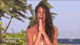 a woman in a bikini is praying in front of palm trees and the words ultima spiaggia on the bottom