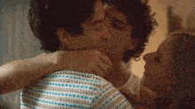 a man and a woman are hugging and kissing .
