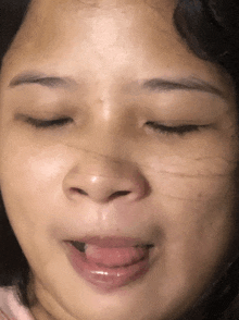 a close up of a woman 's face with her eyes closed and her tongue hanging out