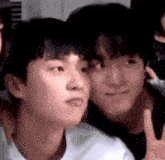 two young men are posing for a picture together and one of them is giving the peace sign .