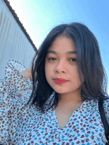 a woman wearing a blue and white floral shirt with red lipstick