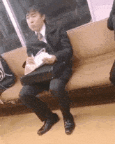 a man is sitting on a couch on a train holding a briefcase .
