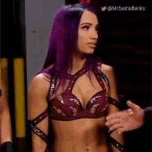 a woman with purple hair is standing next to a man in a wrestling ring .