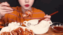 a woman is eating chicken and rice with a spoon