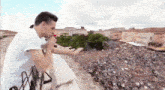 a man in a white shirt stands on a balcony looking at a crowd of people