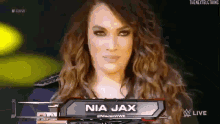 a woman with long curly hair is standing in front of a sign that says nia jax .