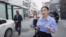 a woman in a blue shirt is walking down the street