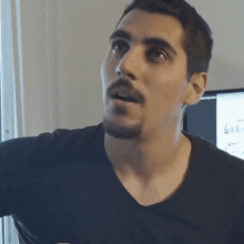 a man with a beard and mustache is wearing a black shirt and looking at something