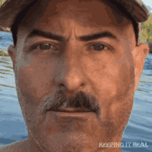 a man with a hat and a mustache has the words keeping it real on the bottom