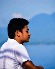 a man in a white shirt is looking at the water