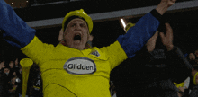 a man wearing a yellow glidden shirt is cheering