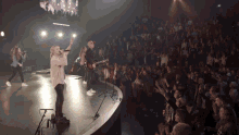 a group of people singing and playing instruments on a stage in front of a crowd