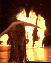 a woman is dancing in front of a huge fire