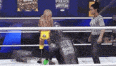 a wrestler is standing in a ring with a referee .