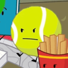 a tennis ball with an angry face is standing next to a box of french fries .