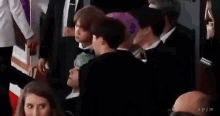 a group of people in suits are sitting in a row on a red carpet .