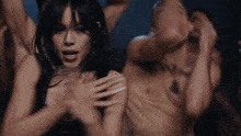 a woman is dancing in front of a group of men without shirts