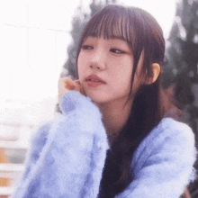 a young woman wearing a blue sweater looks to the side