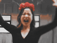 a woman with a red flower on her head is screaming with her arms in the air