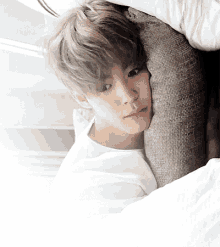 a young man is laying on a bed with his head on a pillow .