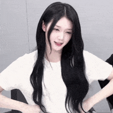 a woman with long black hair is wearing a white shirt and smiling .