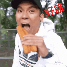 a man wearing a white adidas shirt is eating a donut with his mouth open