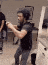a man in a black hat is dancing in a living room with two other men .