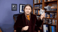 a man in a suit and tie is holding a cd in front of a bookshelf that has the word wizards on it