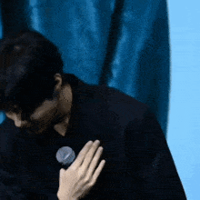 a man in a black jacket is holding a microphone to his chest .