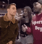 a man wearing a red supers dept sweatshirt is talking to a woman