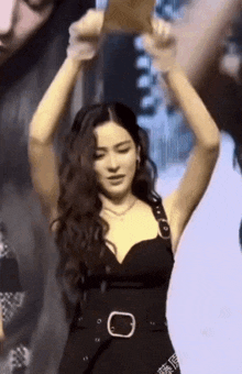 a woman in a black dress is dancing with her hands in the air .