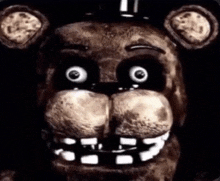 a close up of a teddy bear 's face with glowing eyes and teeth .