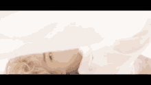 a close up of a person laying on a bed with a white shirt on .