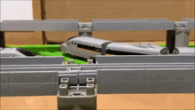 a toy train is going over a bridge in a toy train set .