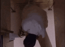 a man in a white shirt and tie is standing in a bathroom .