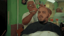 a man is getting his hair cut by a barber in a barber shop