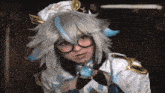 a woman in a white and blue costume with glasses and a blue pendant