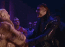 two men are shaking hands in a dark room with purple lights .