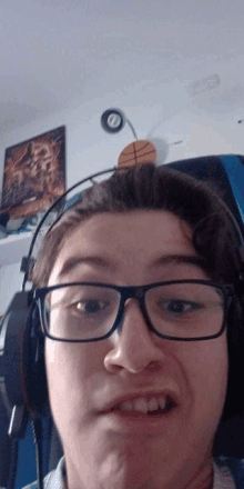 a young man wearing glasses and headphones looks at the camera