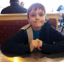 a young boy is sitting at a table in a diner making a funny face