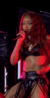 a woman in a bikini is singing into a microphone on a stage in front of a crowd .